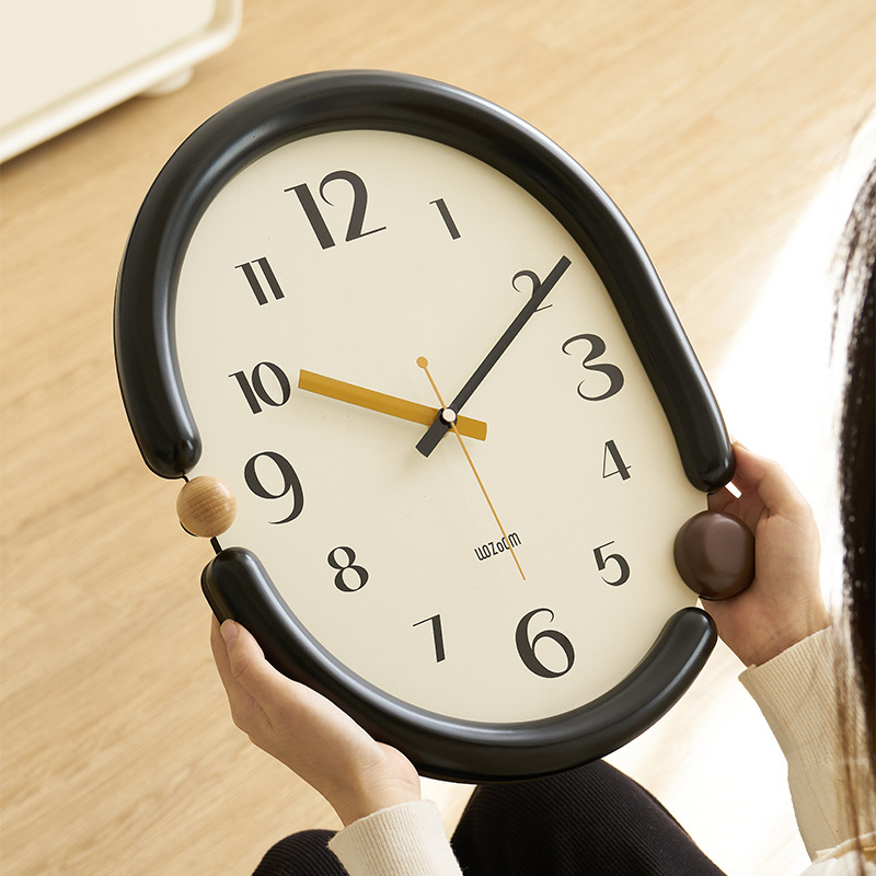 Sienas pulkstenis – ovāla forma, mūsdienīgs minimālisms, sekundes kustība (sweep), analogās rokas, darbojas ar baterijām