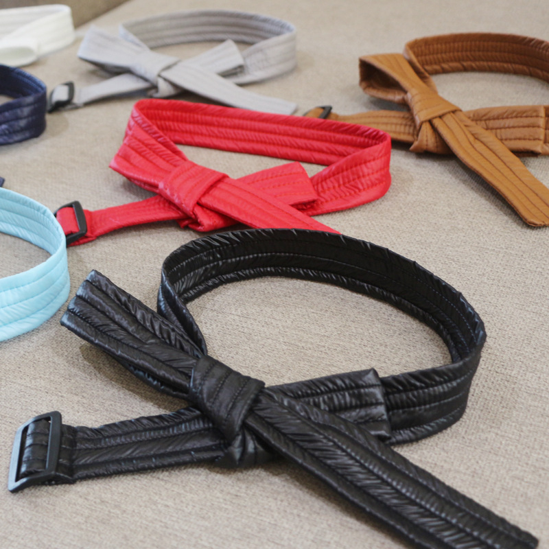 Sieviešu josta kapr­tam ar kokvilnas pildījumu, saitēm ar auklu, austā josta ar plastmasas sprādzi, mašīnas dizains, platums 2–4 cm