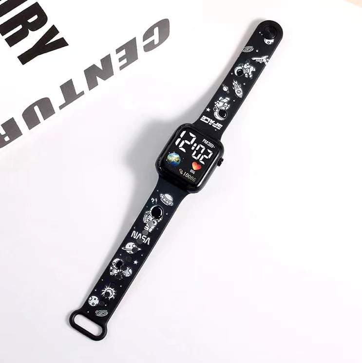 Rokas pulkstenis ar elektronisko kustību un ciparu displeju, karikatūras druka ar sirsniņas formu kvadrāta Zemes motīvā, plastmasas korpuss un siksna (Kustība: Elektroniska; Displejs: Skaitļi; Forma: Kvadrāts; Korpuss: Plastmasas; Siksna: Plastmasas)