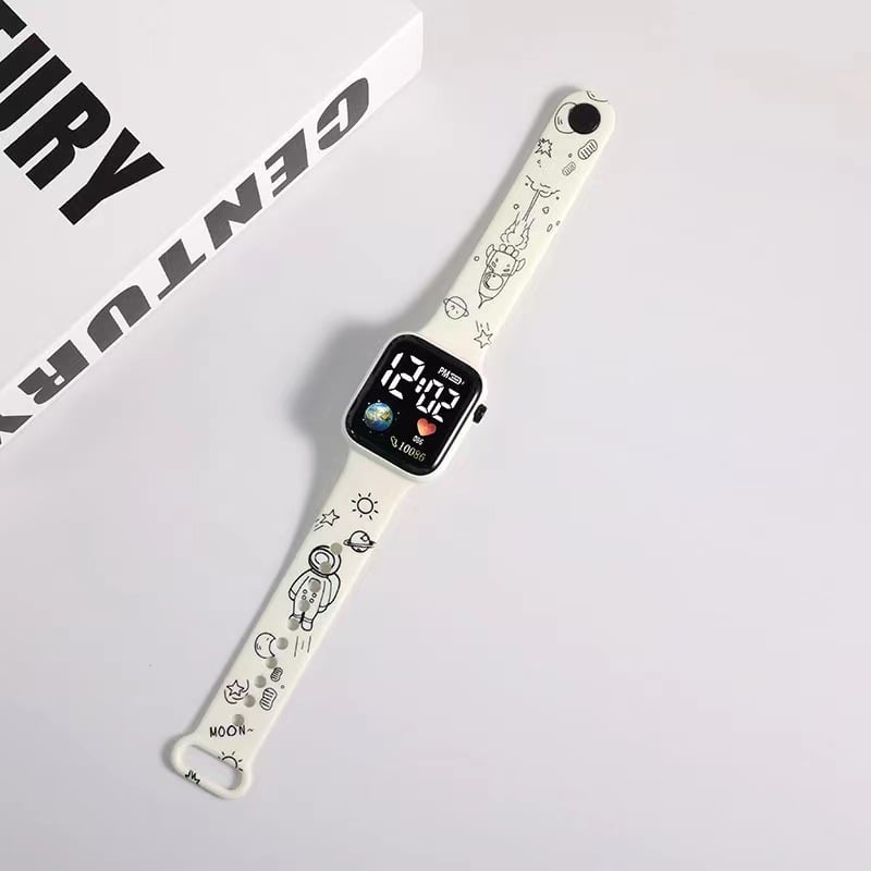 Rokas pulkstenis ar elektronisko kustību un ciparu displeju, karikatūras druka ar sirsniņas formu kvadrāta Zemes motīvā, plastmasas korpuss un siksna (Kustība: Elektroniska; Displejs: Skaitļi; Forma: Kvadrāts; Korpuss: Plastmasas; Siksna: Plastmasas)