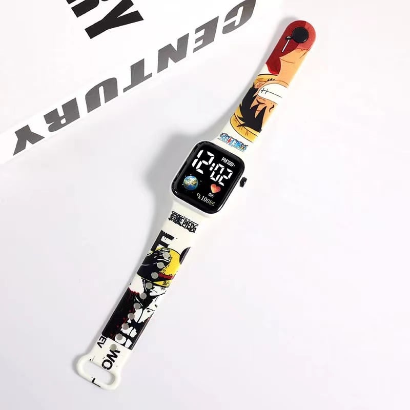 Rokas pulkstenis ar elektronisko kustību un ciparu displeju, karikatūras druka ar sirsniņas formu kvadrāta Zemes motīvā, plastmasas korpuss un siksna (Kustība: Elektroniska; Displejs: Skaitļi; Forma: Kvadrāts; Korpuss: Plastmasas; Siksna: Plastmasas)