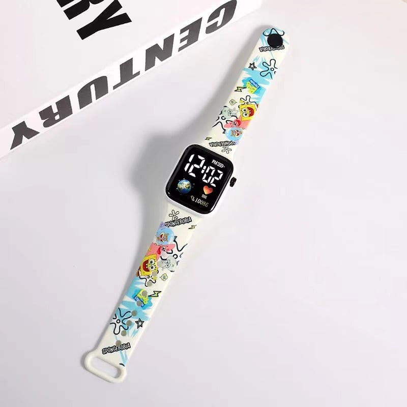 Rokas pulkstenis ar elektronisko kustību un ciparu displeju, karikatūras druka ar sirsniņas formu kvadrāta Zemes motīvā, plastmasas korpuss un siksna (Kustība: Elektroniska; Displejs: Skaitļi; Forma: Kvadrāts; Korpuss: Plastmasas; Siksna: Plastmasas)