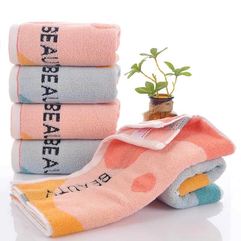 Kokvilnas sejas dvielis ar biezu tekstūru, mīksts un labi uzsūcošs; burti izšūti krāsu blokos (Materiāls: kokvilna; Diegi: 16s; Ražošanas process: apdare, vienkāršs audums; Svars: 120–140 g; Tips: sejas dvielis)