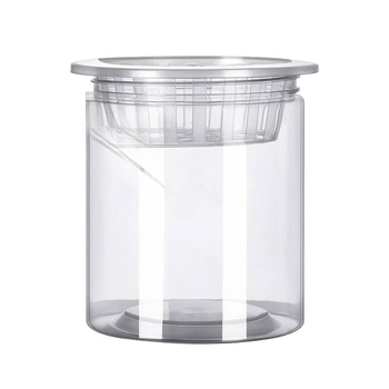 Caurspīdīgs plastmasas cilindrisks hydroponiskais pods sēklām un maziem augiem, stāvošs uz grīdas ar stādīšanas grozu, domāts mājas un dārza lietošanai