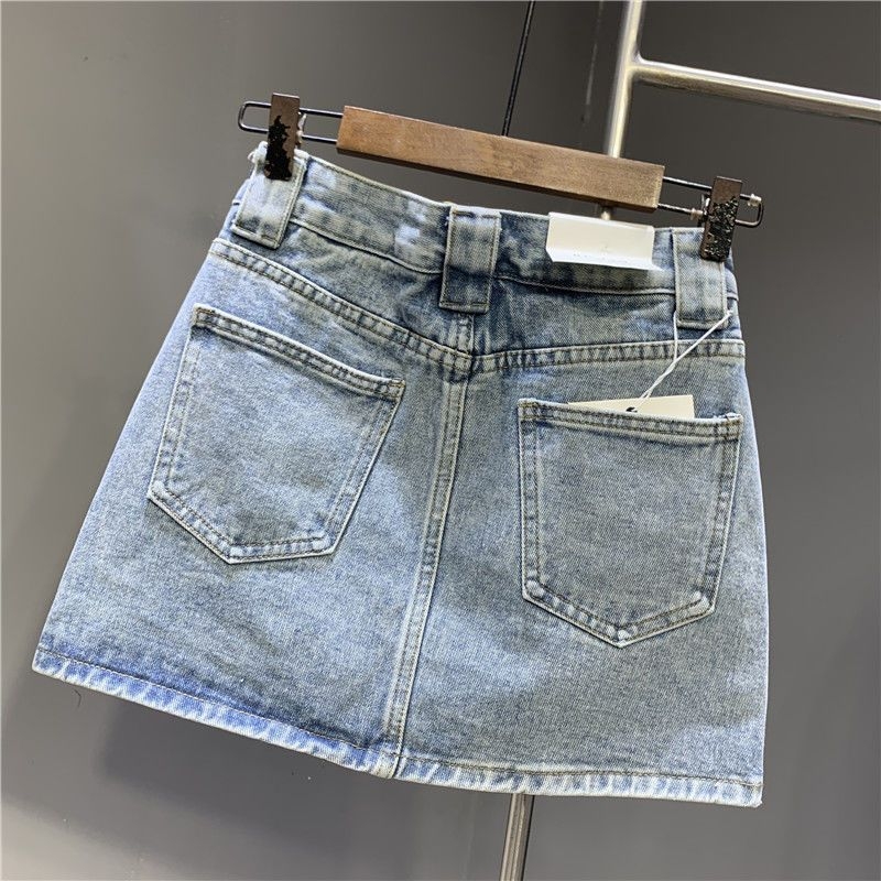 A-linijska denimska suknja s izbrušenim detaljima, zipom i gumbima – pamukasti denim, gradski stil, ljeto 2024