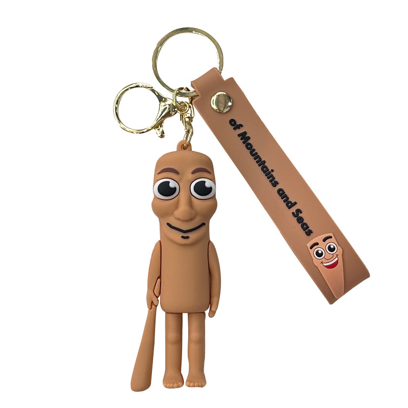 Breloc din PVC cu o figurină din lemn în formă de omuleț, purtând pantofi, și un pandantiv rechin