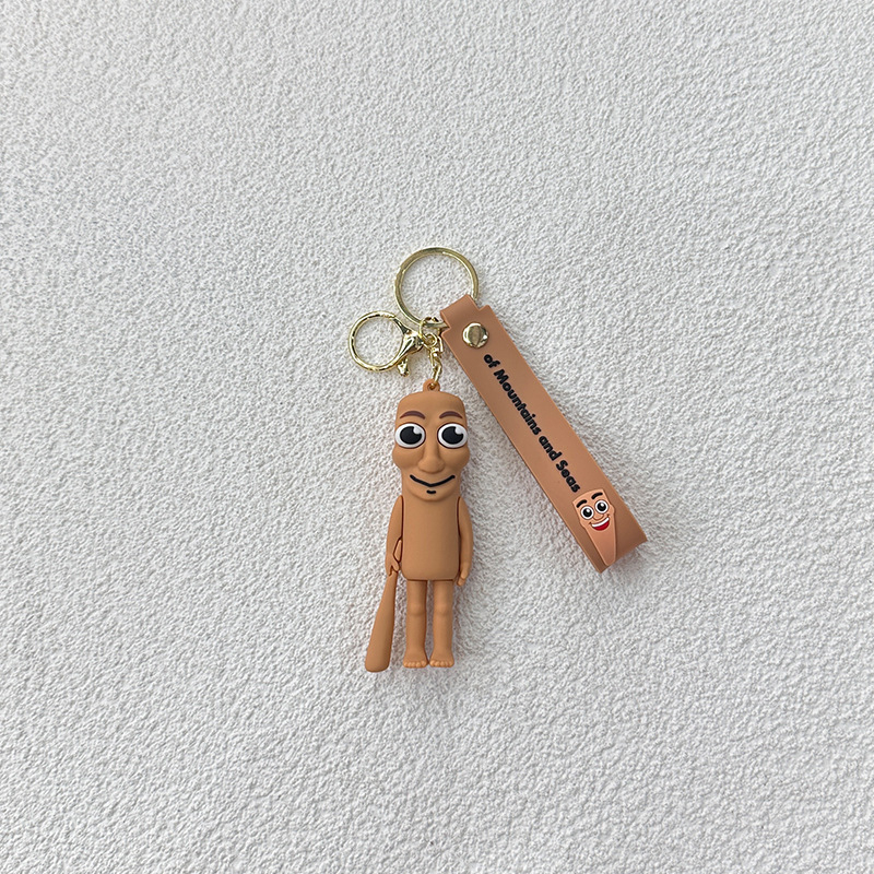 Breloc din PVC cu o figurină din lemn în formă de omuleț, purtând pantofi, și un pandantiv rechin