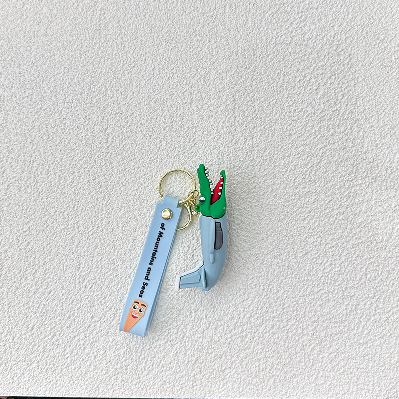 Breloc din PVC cu o figurină din lemn în formă de omuleț, purtând pantofi, și un pandantiv rechin