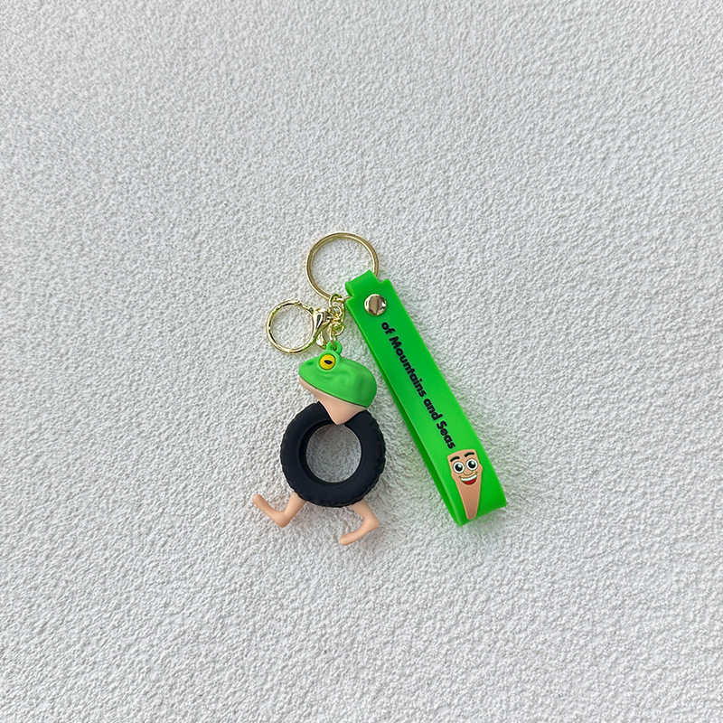 Breloc din PVC cu o figurină din lemn în formă de omuleț, purtând pantofi, și un pandantiv rechin