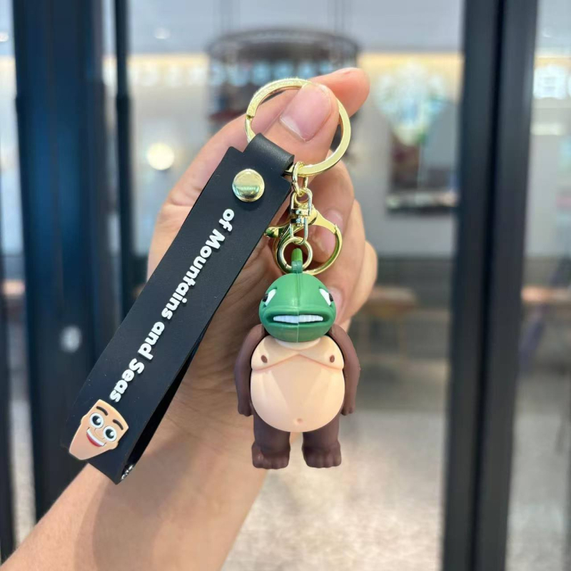 Breloc din PVC cu o figurină din lemn în formă de omuleț, purtând pantofi, și un pandantiv rechin