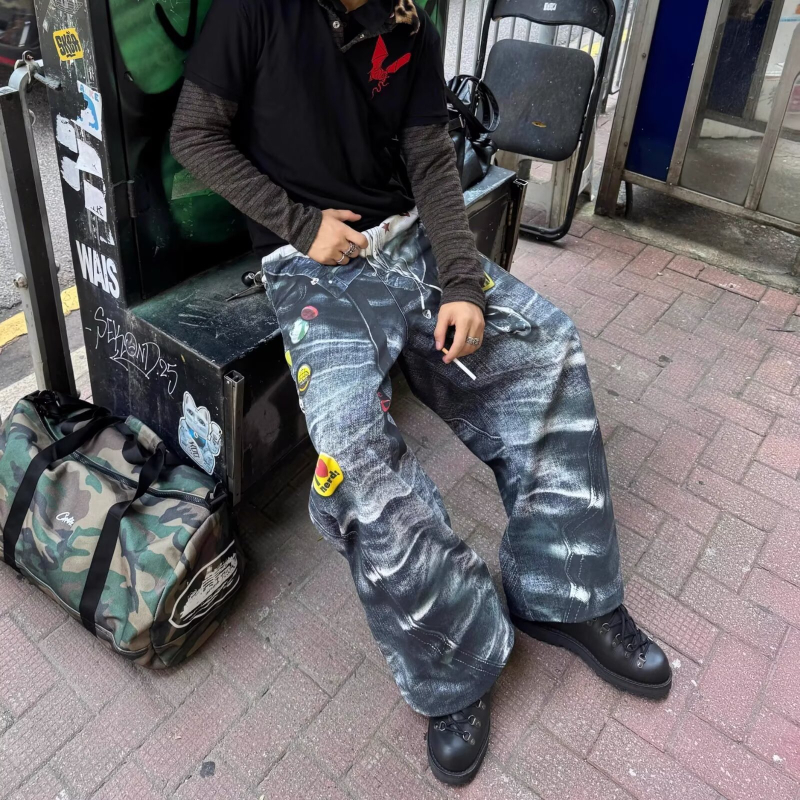 Traperice s graffiti otiskom, poderane detalje, širok i ležeran kroj, pamukasti denim, niska struka