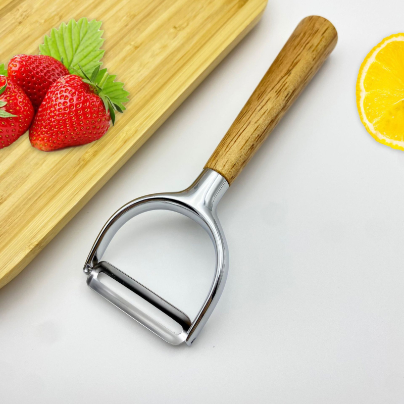 Multifunkcionális cinkötvözetből készült hántoló tölgyfa fogantyúval — hántolás, kaparó, gyümölcs- és zöldségpucoló, dinnyepucoló; logó nyomtatás; testreszabás elérhető