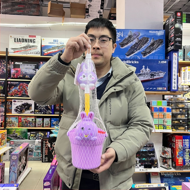 Set de jucării pentru plajă pentru copii, cu unelte pentru nisip și jocuri cu apă, include găleți și lopățile, potrivit pentru 4–6 ani, ambalat într-o plasă.