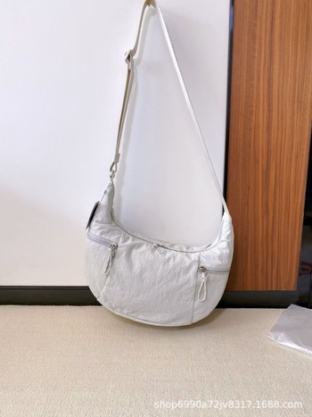 Torba preko ramena u urbanom minimalističkom stilu — platnena, oblik dumpling, zatvaranje zatvaračem, unutarnji džepovi za telefon i dokumente