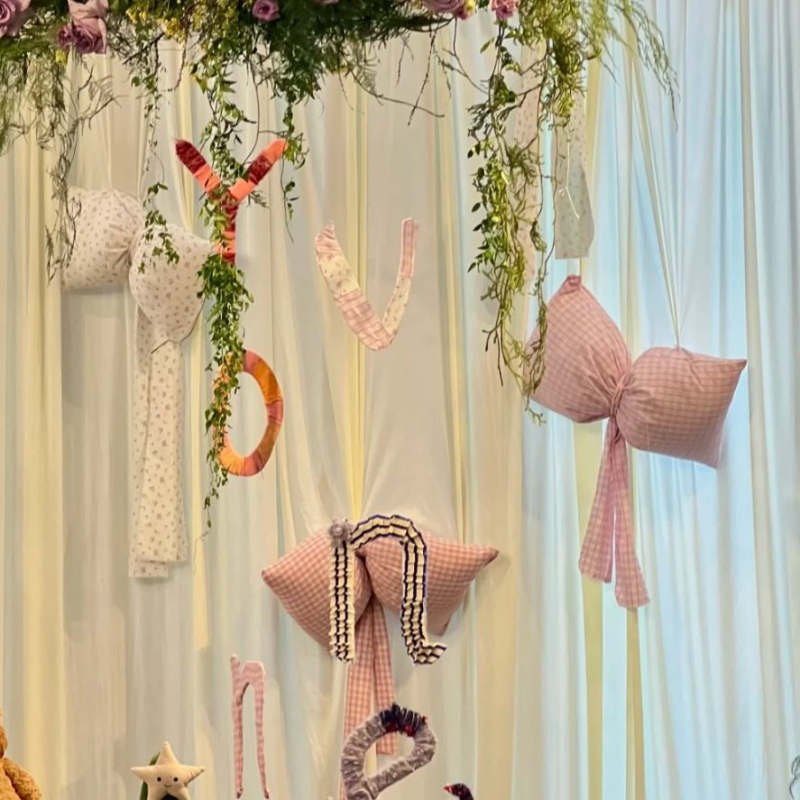 Kockás masnival ellátott textilhátfal rendezvényekhez — selyemvirágokkal, aranyos stílus, helyszín-elrendezési kellék