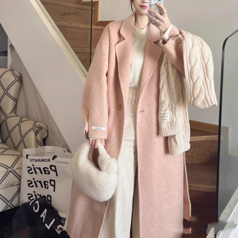 Ženski vuneni kaput, srednje duljine, opuštenog kroja, dvostruko kopčanje, ovratnik stila sakoa, dugi rukavi, ručno šiveno