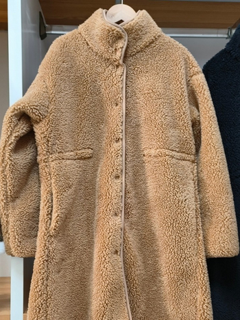 Palton damă, lungime medie, croială lejeră, guler înălțat; fleece din lână de miel artificială; principal poliester 70–80%, cașmir <30%