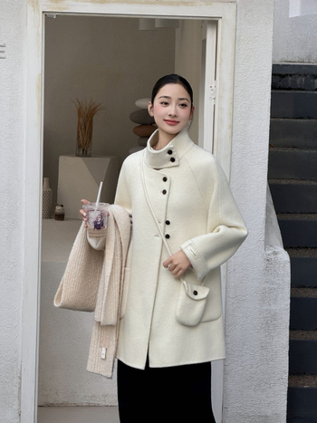 Női visszafordítható gyapjú kabát, középméretű hossz, álló gallér, laza szabás, elülső zárás több gombbal.