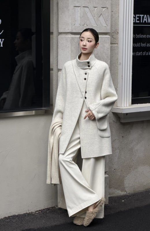 Női visszafordítható gyapjú kabát, középméretű hossz, álló gallér, laza szabás, elülső zárás több gombbal.