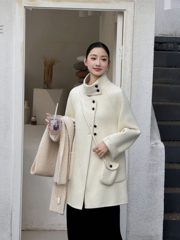 Női visszafordítható gyapjú kabát, középméretű hossz, álló gallér, laza szabás, elülső zárás több gombbal.