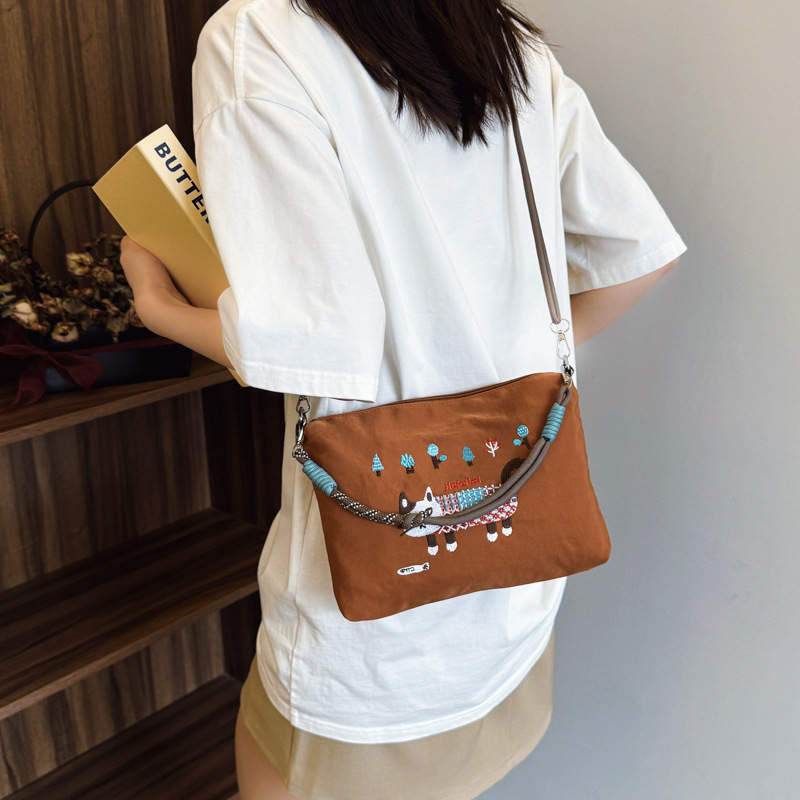 Krosbody torba preko jednog ramena – velik kapacitet, vodootporan materijal, izvezen motiv mačice, zatvarač, podstava od poliestera