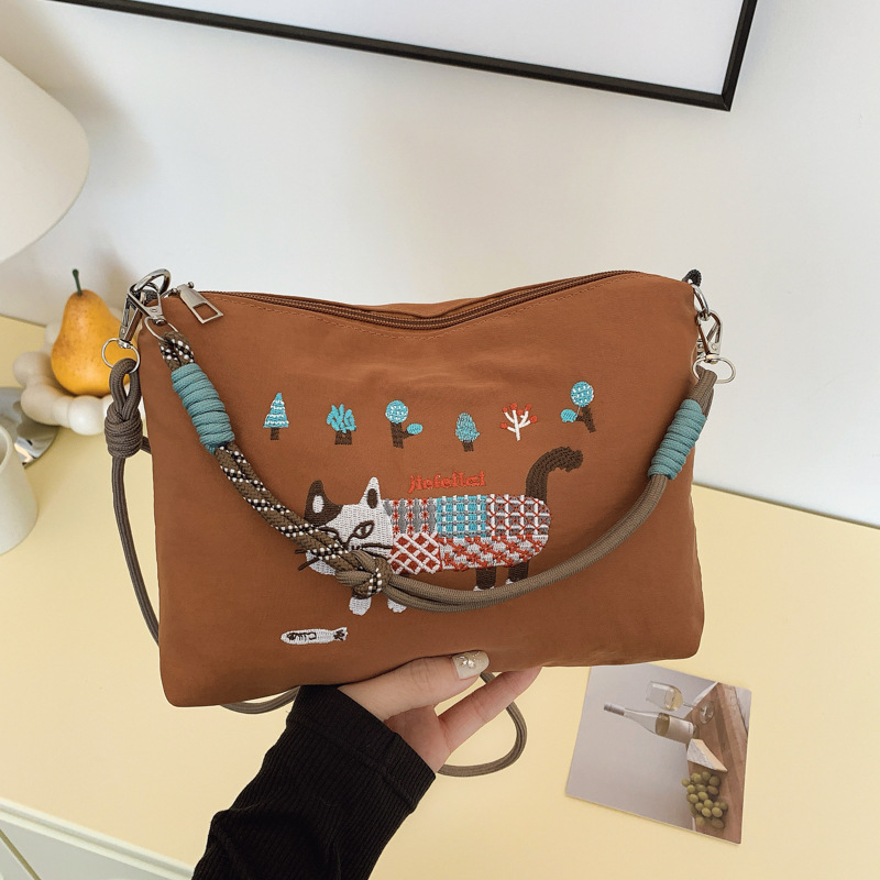 Krosbody torba preko jednog ramena – velik kapacitet, vodootporan materijal, izvezen motiv mačice, zatvarač, podstava od poliestera