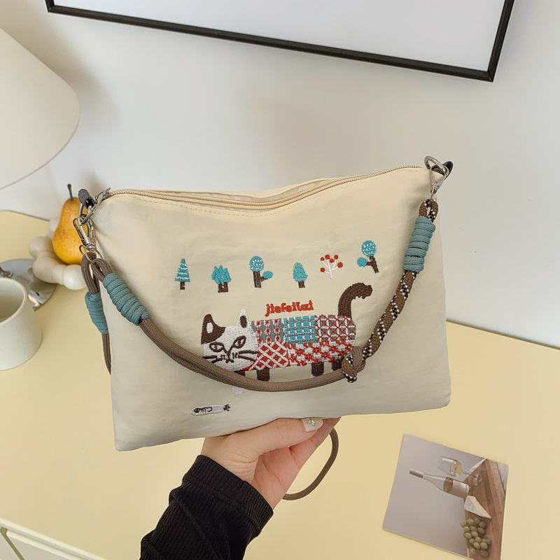 Krosbody torba preko jednog ramena – velik kapacitet, vodootporan materijal, izvezen motiv mačice, zatvarač, podstava od poliestera