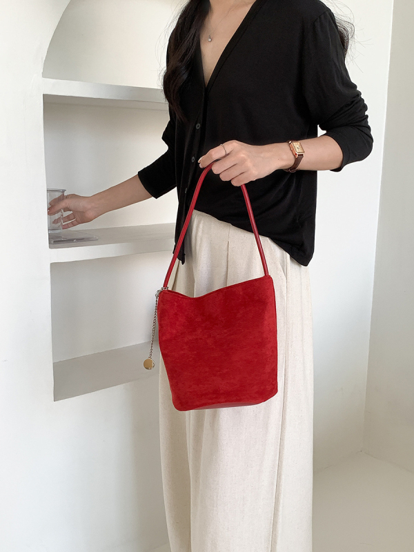 Suede bucket bag cilindričnog oblika s magnetskim zatvaračem; unutarnja džep s džepom na zatvarač, džep za mobitel i džep za ID.