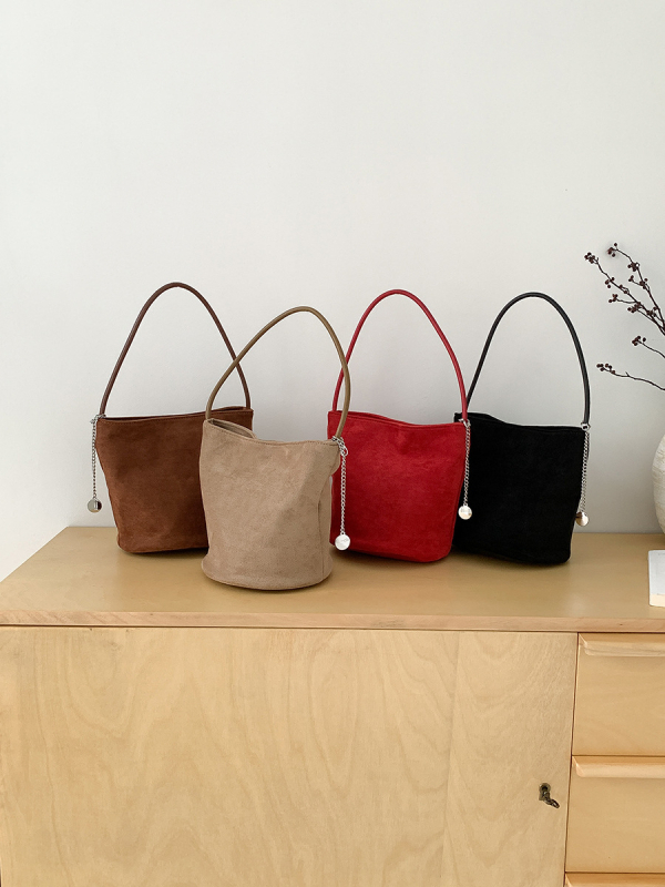 Suede bucket bag cilindričnog oblika s magnetskim zatvaračem; unutarnja džep s džepom na zatvarač, džep za mobitel i džep za ID.