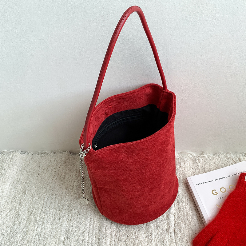Suede bucket bag cilindričnog oblika s magnetskim zatvaračem; unutarnja džep s džepom na zatvarač, džep za mobitel i džep za ID.