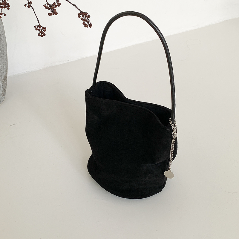 Suede bucket bag cilindričnog oblika s magnetskim zatvaračem; unutarnja džep s džepom na zatvarač, džep za mobitel i džep za ID.