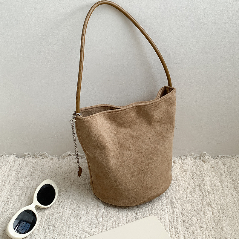 Suede bucket bag cilindričnog oblika s magnetskim zatvaračem; unutarnja džep s džepom na zatvarač, džep za mobitel i džep za ID.