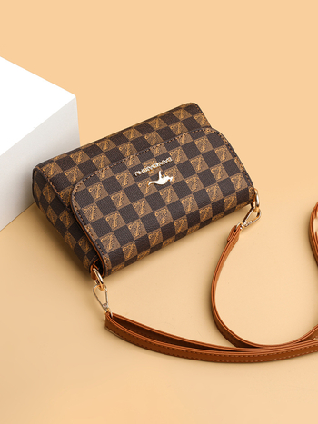 Ženska crossbody torba kvadratnog oblika, PVC materijal, podstava poliester, zatvaranje kapicom, unutarnji džepovi: zip pretinac, džep za mobitel, svakodnevna upotreba, jesen 2023
