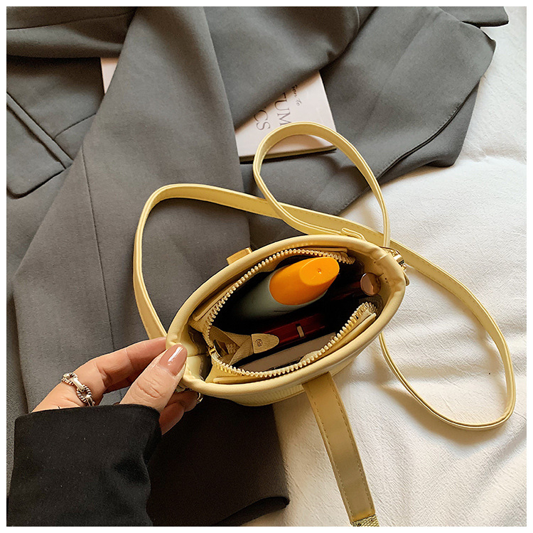 PU anyagú kancsó alakú válltáska, városi minimalist stílus, záródó csattal, poliészter bélés, egypántos vállpánt, belső cipzáras zseb és telefonzseb.