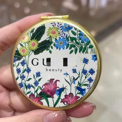 Oglindă de machiaj din metal, pliabilă, cu două fețe, rotundă, argintie.