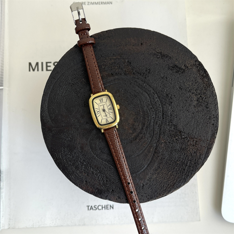 Ženski sat s vintage inspiracijom, zlatnog tona, kvarcni mehanizam, cifernik s rimskim brojevima, tanak remen, casual minimalistički stil.