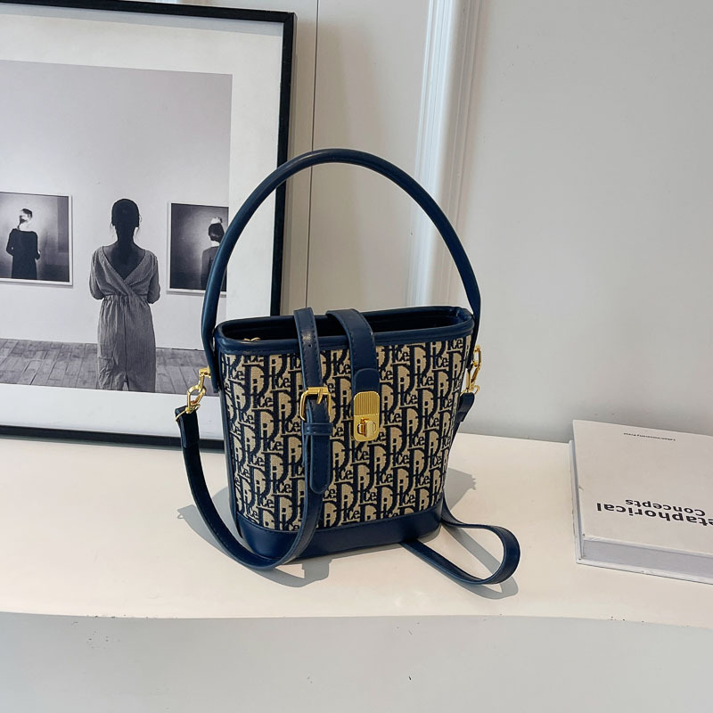 Ženska torba tipa kanta s natpisom, vintage izgled, zaključavanje bravom, za rame ili crossbody.