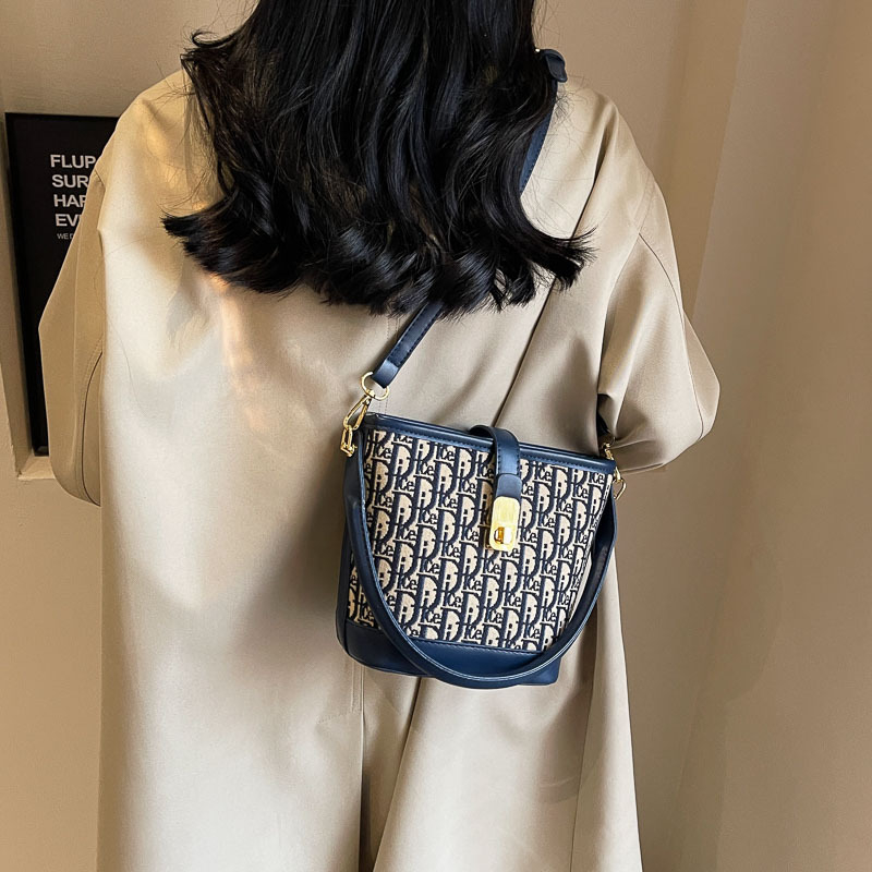 Ženska torba tipa kanta s natpisom, vintage izgled, zaključavanje bravom, za rame ili crossbody.
