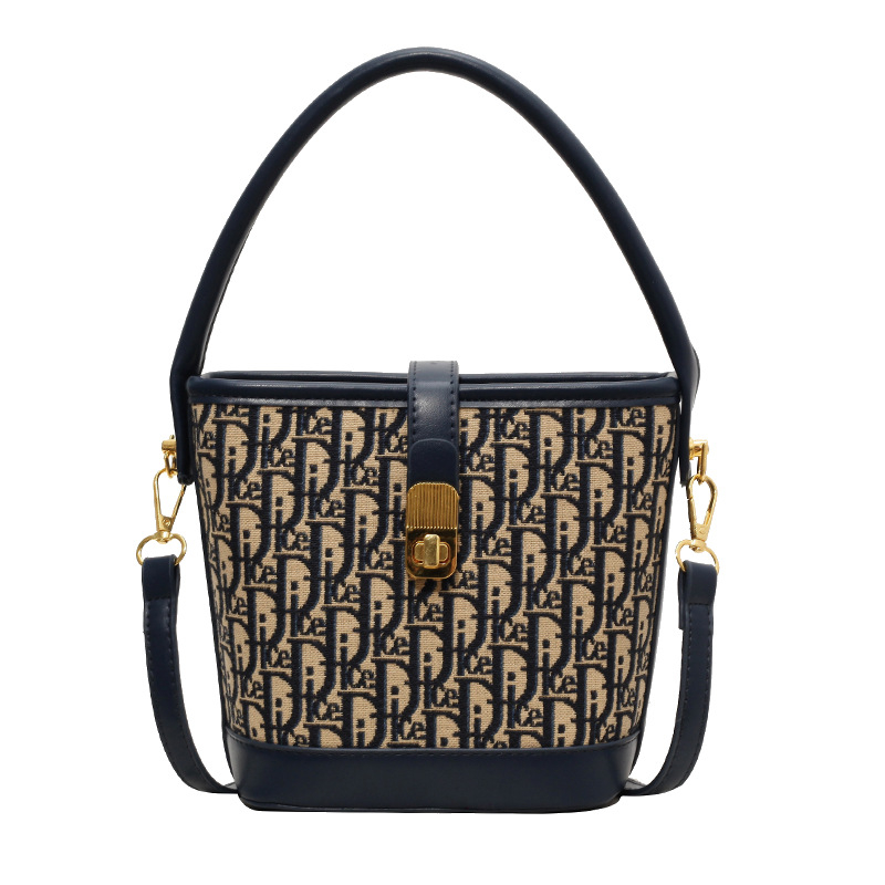 Ženska torba tipa kanta s natpisom, vintage izgled, zaključavanje bravom, za rame ili crossbody.