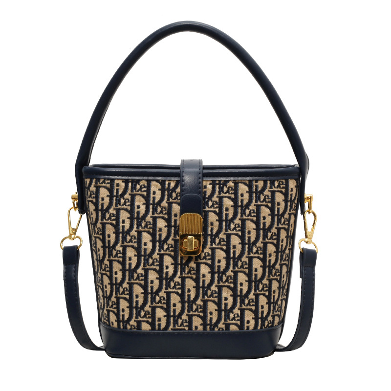 Ženska torba tipa kanta s natpisom, vintage izgled, zaključavanje bravom, za rame ili crossbody.