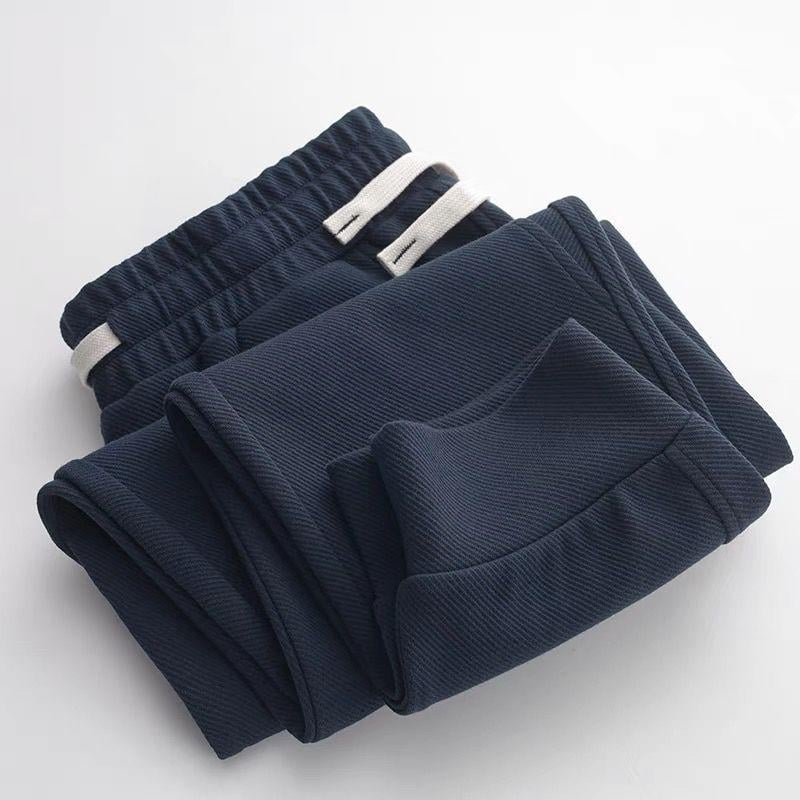 Teške jogger hlače od twill tkanine u tamnoplavojoj boji, širokog kroja, duge, s manžetom pri gležnjevima, sportsko- casual