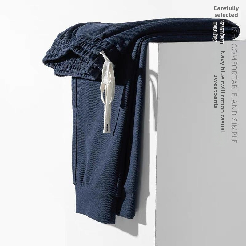 Teške jogger hlače od twill tkanine u tamnoplavojoj boji, širokog kroja, duge, s manžetom pri gležnjevima, sportsko- casual