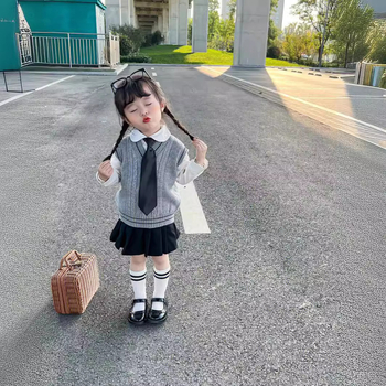 Lányok japán stílusú iskolai egyenruha szoknyával és kötött hosszú ujjú mellényes szettel