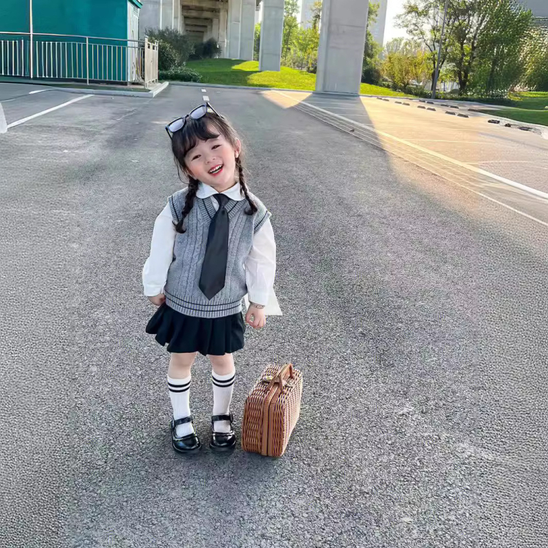 Lányok japán stílusú iskolai egyenruha szoknyával és kötött hosszú ujjú mellényes szettel