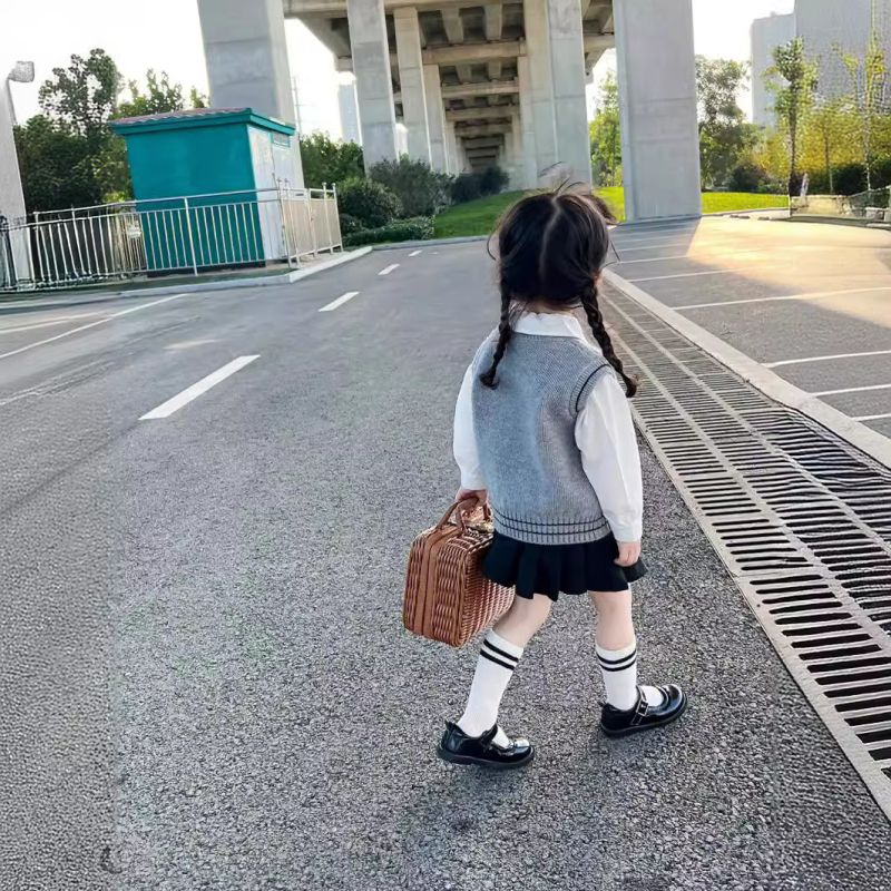 Lányok japán stílusú iskolai egyenruha szoknyával és kötött hosszú ujjú mellényes szettel