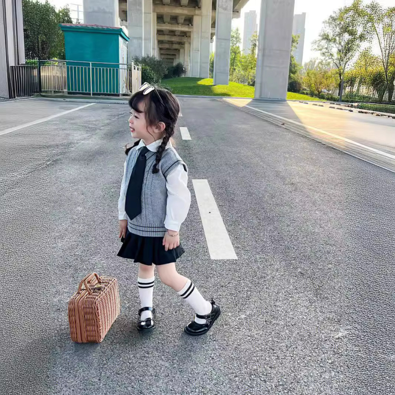 Lányok japán stílusú iskolai egyenruha szoknyával és kötött hosszú ujjú mellényes szettel