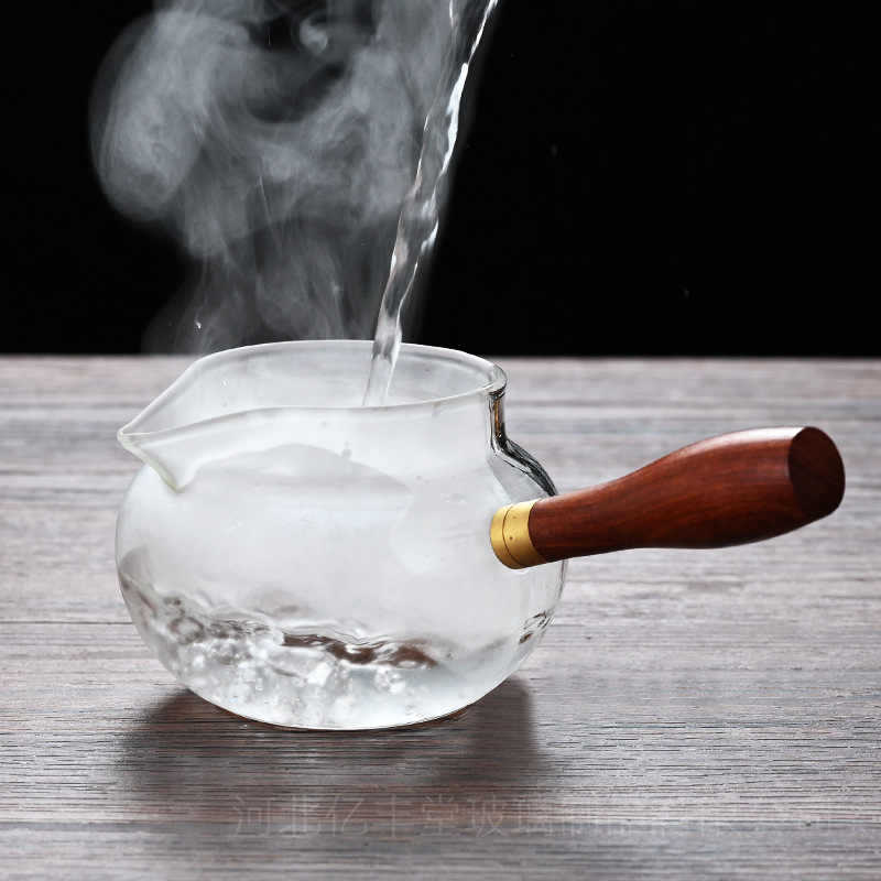 Set Gongfu pentru ceai din sticlă borosilicat rezistentă la căldură, cu mâner lateral din lemn; include cană de servire a ceaiului și ceașcă de distribuție egală.