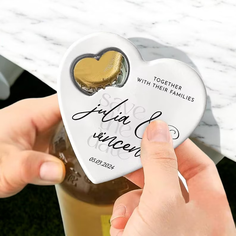Magnet de frigider personalizat în formă de inimă cu deschizător de sticle; posibilitatea imprimării logo-ului; cadou versatil pentru nunți, zile de naștere și alte ocazii.