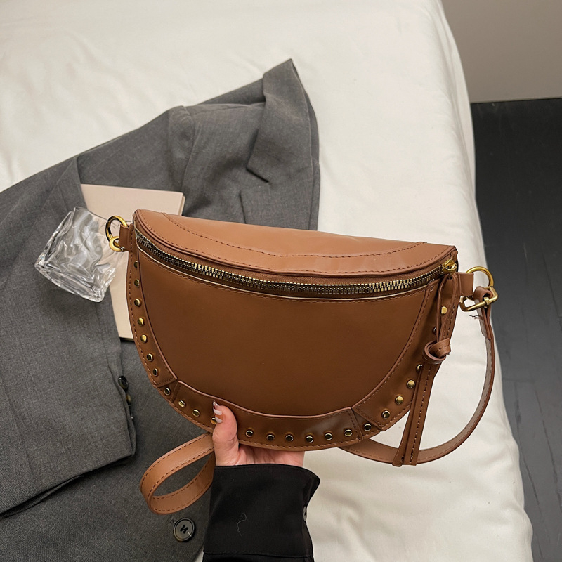 Ženska sedlast torba, casual minimalistički dizajn, jesen 2025, s detaljima od zakovica, lagani luksuz, crossbody torba preko jednoga ramena.