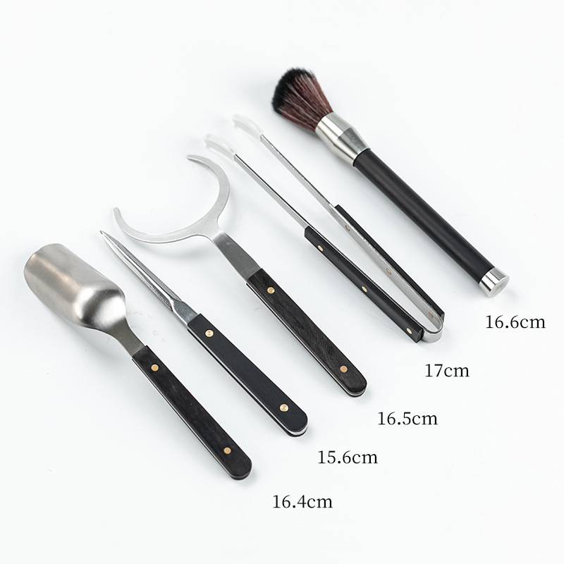 Set ceremonie ceai – șase domni, oțel inoxidabil, cu accente din lemn, cinci piese accesorii: clips pentru ceai, linguriță, ac pentru ceai și pix pentru prepararea ceaiului.